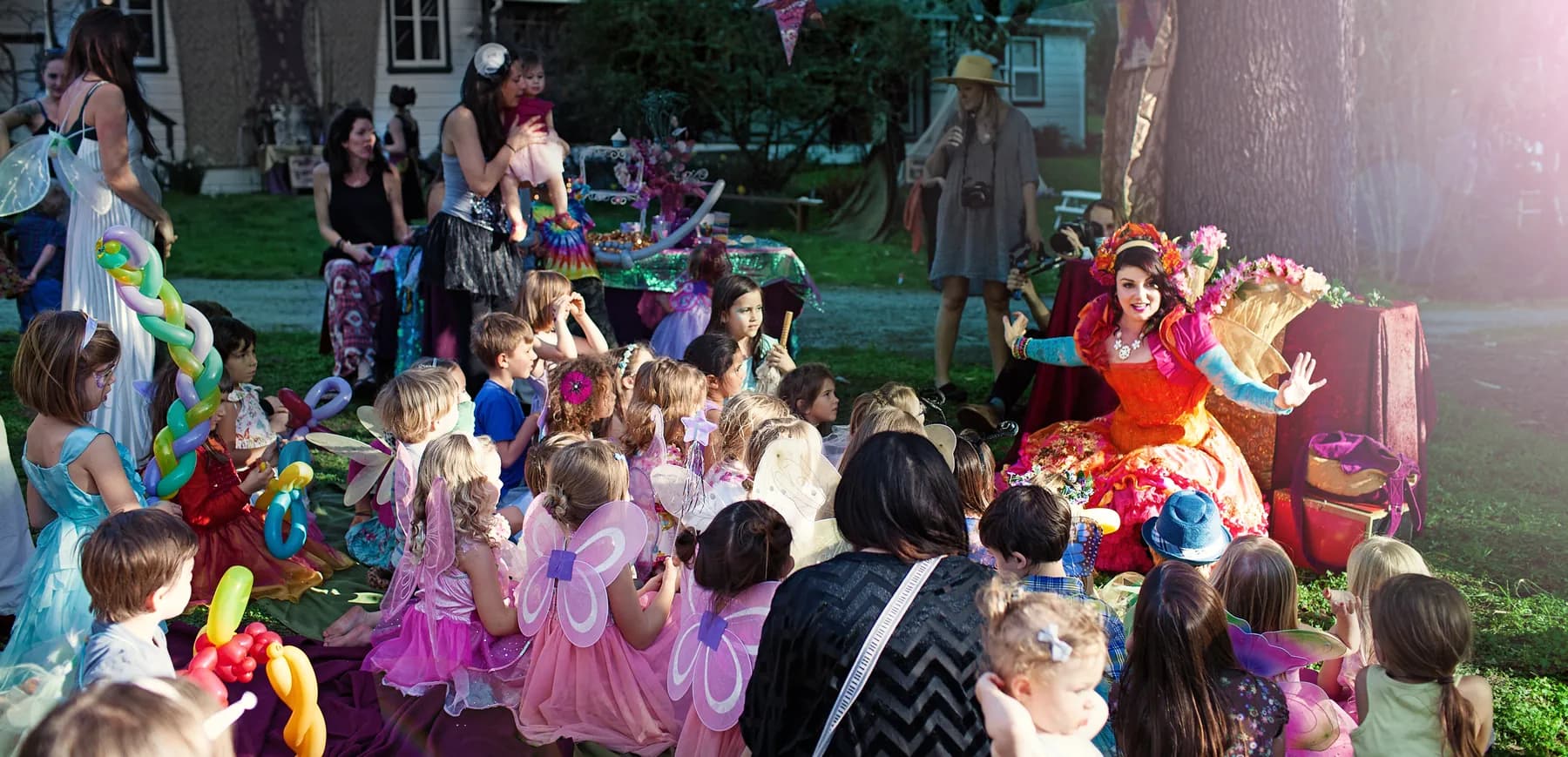 A crowd of delighted children gathered around a Happily Ever Laughter faerie at an event
