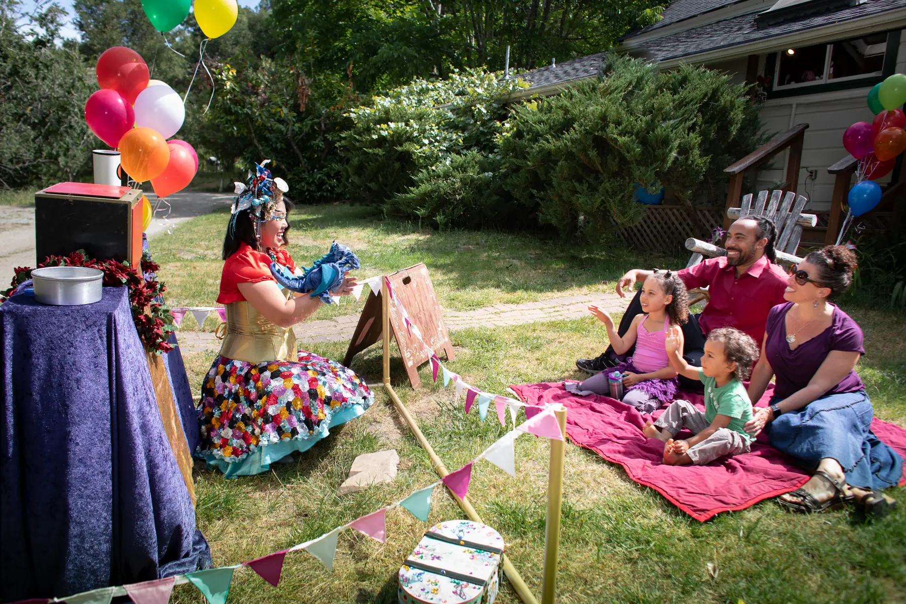 A Happily Ever Laughter faerie performing for a smiling family seated on a picnic blanket