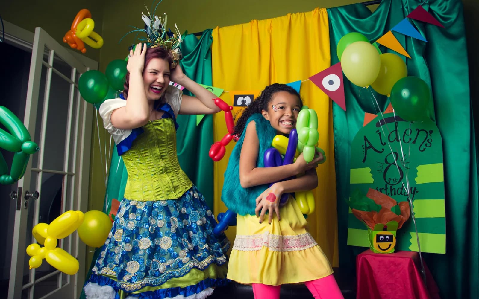 A Happily Ever Laughter balloon twister making a balloon animal for a smiling child at a party.