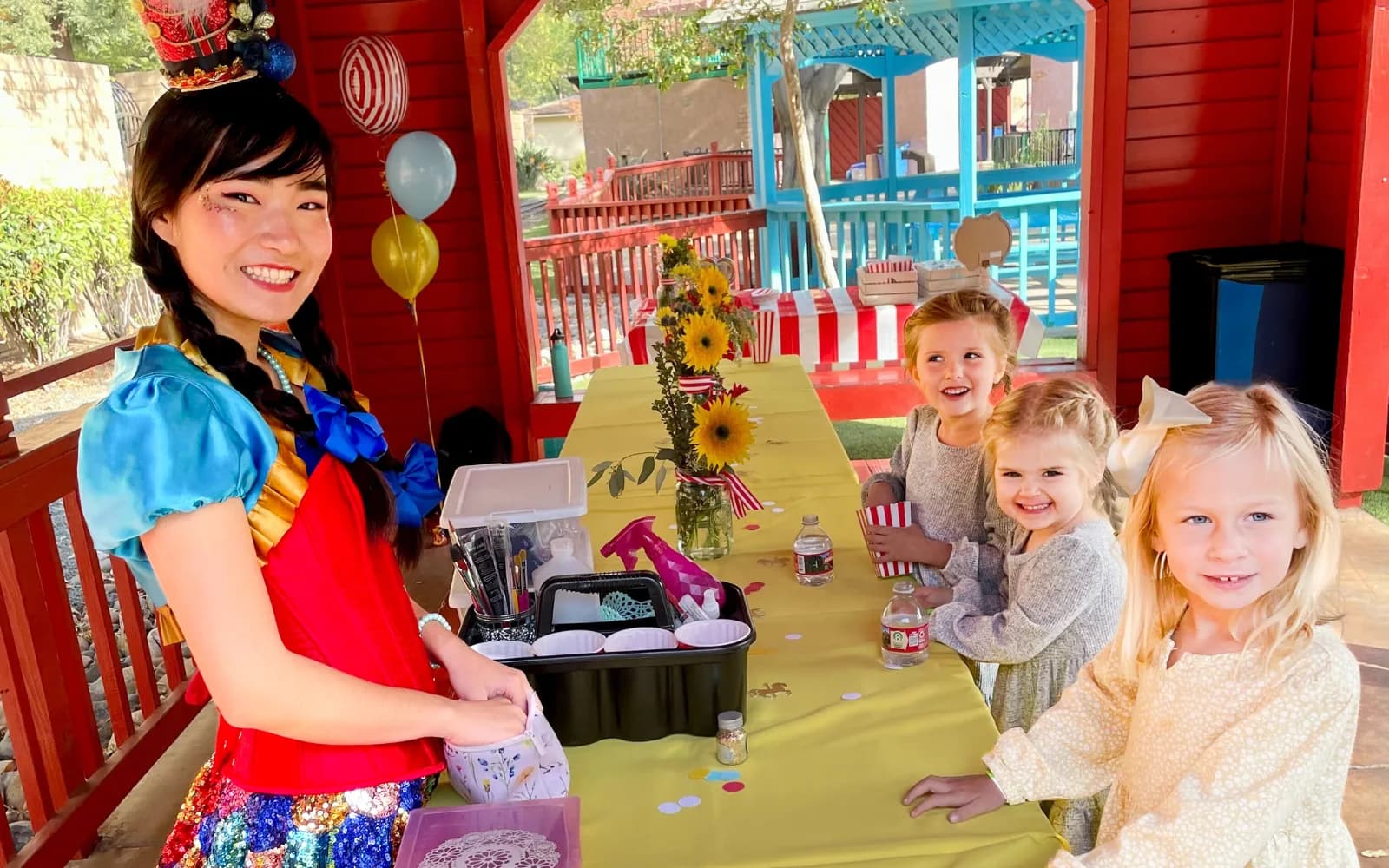A Happily Ever Laughter craft leader helping a smiling child make a craft at a party.