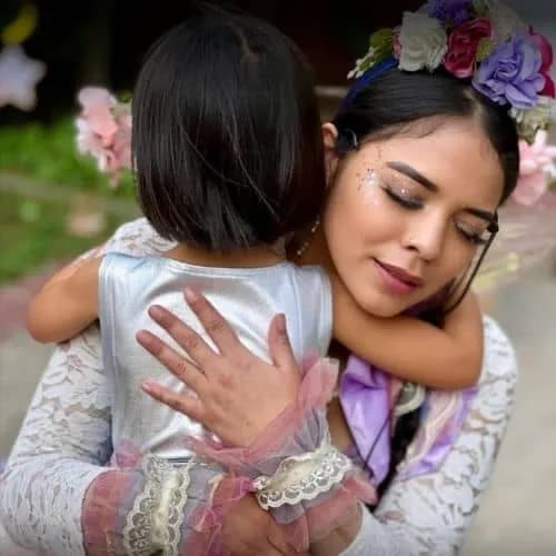 A Happily Ever Laughter faerie hugging a child who has warmed up to her at an event.