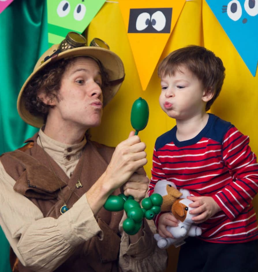 A Happily Ever Laughter face painter in a jester costume sharing a playful moment with a smiling boy at an event.