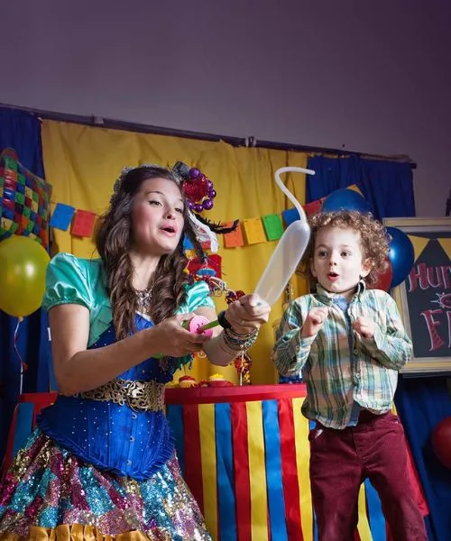 A faerie twisting a balloon for a child at a birthday party