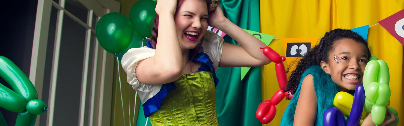 A Happily Ever Laughter twister handing a child a colorful balloon animal.