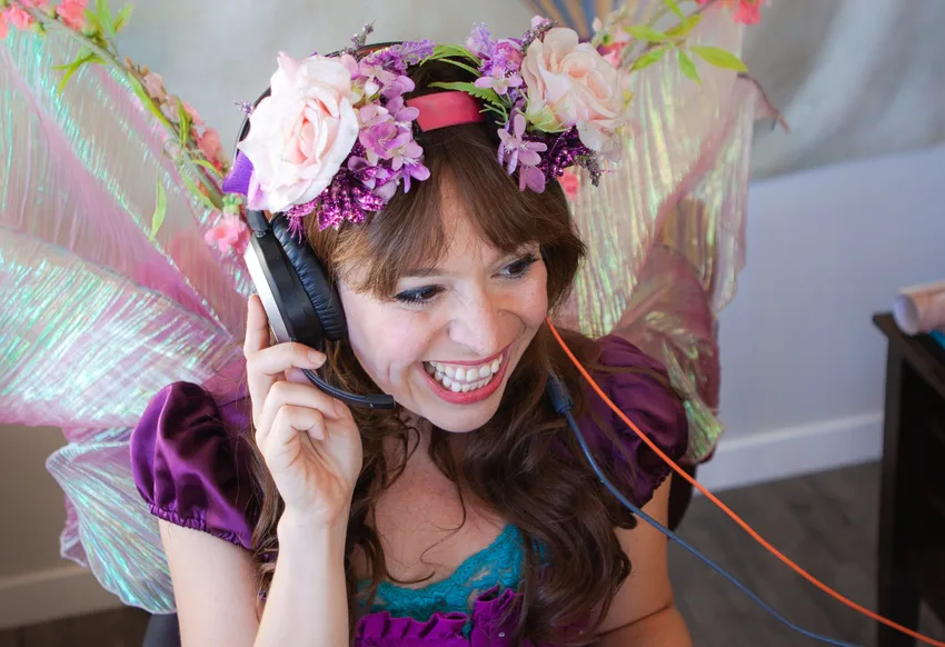 A Happily Ever Laughter party faerie taking a call at her desk