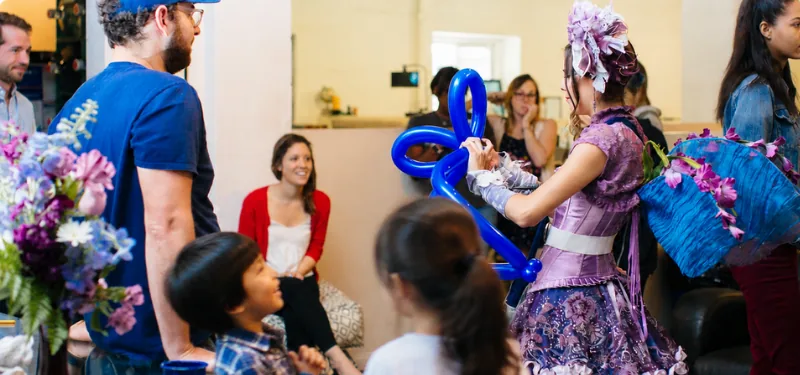 A performer leading a group of happy children in an activity at a company event.