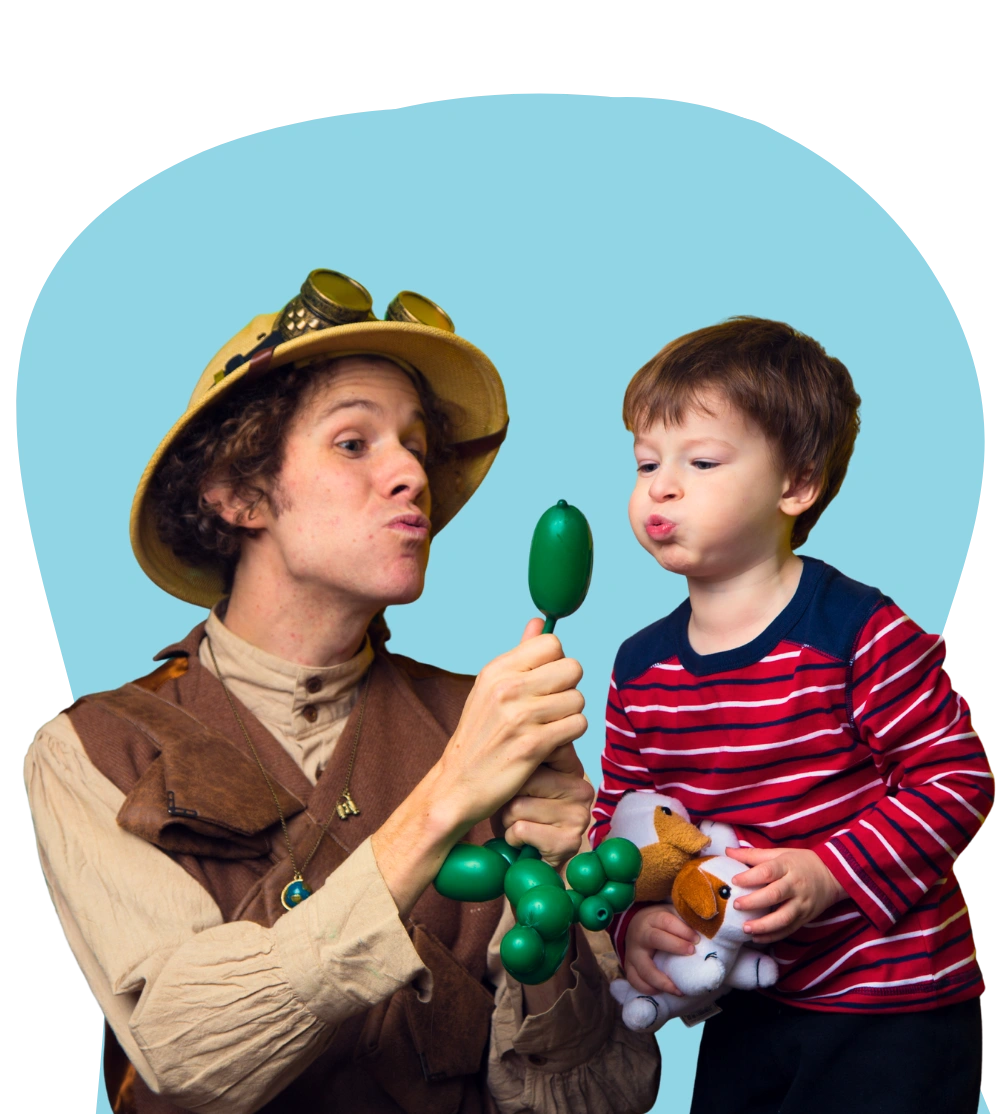 A Happily Ever Laughter balloon twister in a jester costume holding a green balloon animal for a child.