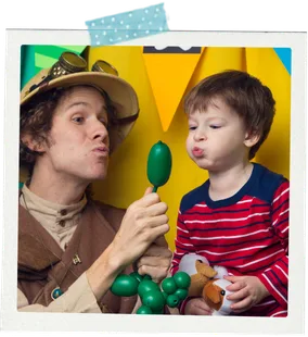 A child at a party holding a balloon animal a Happily Ever Laughter twister just made.