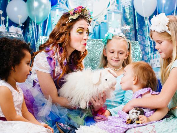 Happily Ever Laughter performer delighting a group of children with a soft easter bunny puppet in a winter wonderland setting, perfect for immersive and whimsical party entertainment in California.