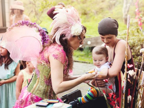 Happily Ever Laughter performer interacting with a baby and their parent, offering engaging and family-friendly entertainment for special events and outdoor gatherings in California.